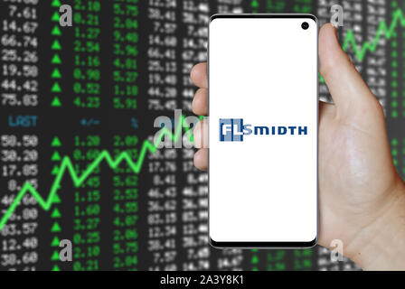 Un homme est titulaire d'un téléphone d'afficher le logo de société FLSmidth & Co. énumérés sur OMX Copenhagen. Marché des actions positives. Credit : PIXDUCE Banque D'Images