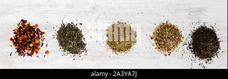 Vue de dessus de grappes de divers types de thé sur une surface en bois blanc. Banque D'Images