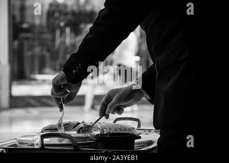 Un serveur expérimenté qui sert un délicieux petit-déjeuner grillé dans un restaurant élégant. Banque D'Images