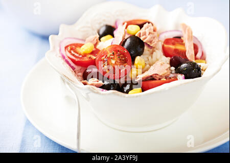 Salade de riz au thon, tomates cerises juteuses, les haricots rouges, olives noires, maïs sucré, oignons rouges et basilic frais. Banque D'Images