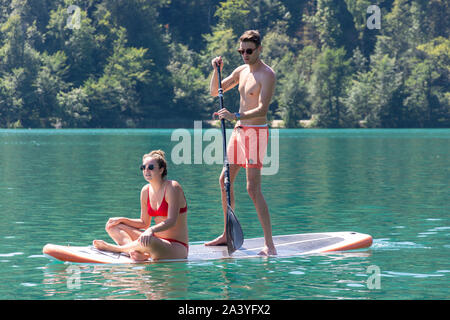 Jeune couple paddleboarding près de l'île de Bled, le lac de Bled, Bled, Slovénie, la région de la Haute-Carniole Banque D'Images