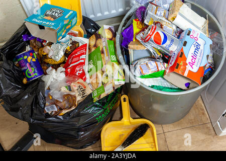 WELWYN GARDEN CITY, ROYAUME UNI - 10 octobre 2019 : Noir sac à déchets en plastique débordant de détritus à côté d'une case pleine dans une cuisine sale Banque D'Images