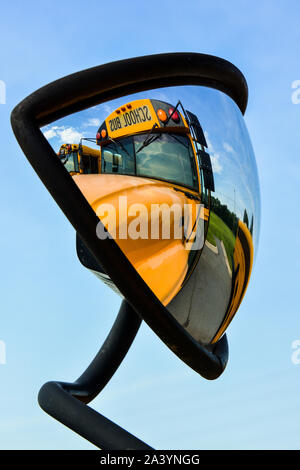 Un autobus scolaire jaune se reflète dans son propre grand miroir du côté de la création d'un intéressant point de vue abstrait de ce mode de transport. Banque D'Images