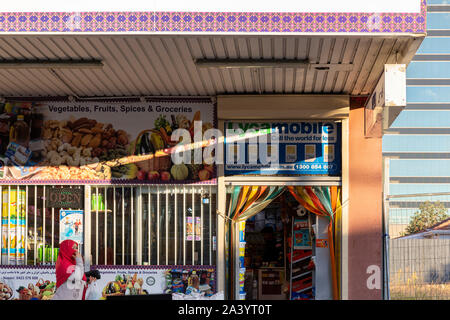 Les femmes portant foulard rouge marchant devant le lait local bar. Banque D'Images