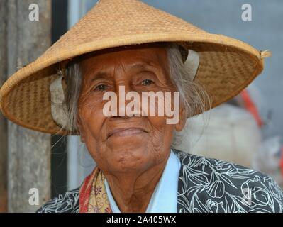 Vieux marché javanais femme porte un chapeau de paille conique asiatiques (caping). Banque D'Images