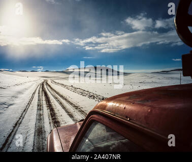 Jeep rouge roulant le long d'un chemin couvert de neige sur l'Altiplano en Bolivie Banque D'Images