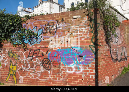 Graffitis colorés sur un mur de brique à St Leonards-on-Sea, East Sussex, UK Banque D'Images