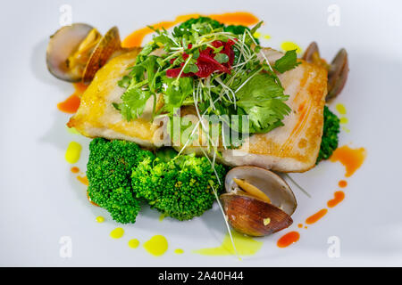 Plaque en céramique blanche avec filet de mahi-mahi et les palourdes avec le brocoli, l'oignon, persil et fèves germées. Vue d'en haut. Banque D'Images