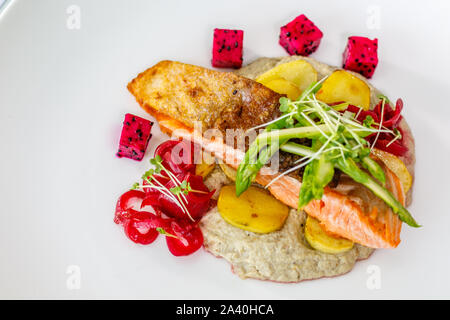 Peau croustillante avec du saumon de l'Atlantique, de pommes de terre rôties asperges sautées et Baba Ghanoush, décorées avec des fèves germées et fruit du dragon. Vue d'en haut Banque D'Images