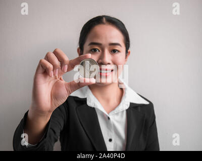 Femme d'affaires montrant ethereum silver coin sur le mur blanc est l'arrière-plan. Les investisseurs girl ethereum coin d'extraits dans l'Internet. Banque D'Images