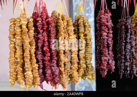 Churchkhela aux noix rouge, jaune et brun accroché à un thread sur le comptoir. Sucreries traditionnelles en Géorgie. Délicieux et sain desse géorgienne Banque D'Images