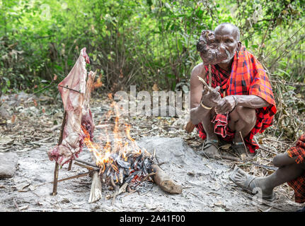 Arusha, Tanzanie, 7ème Septembre 2019 : homme Massaï la cuisson des viandes sur le feu Banque D'Images