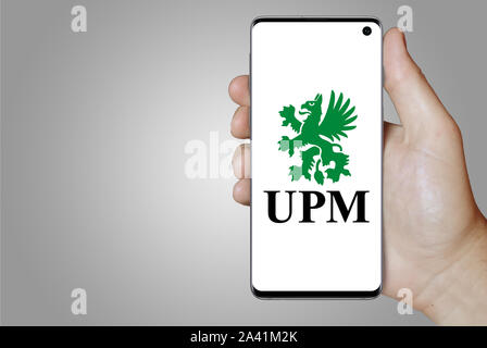 Un homme est titulaire d'un téléphone d'afficher le logo de société UPM-Kymmene énumérés sur OMX Helsinki. Fond dégradé de gris. Credit : PIXDUCE Banque D'Images