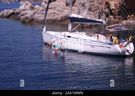 Trois garçons d'un yacht au large de plongée dans la mer d'un bateau à voile en off les îles grecques. Banque D'Images