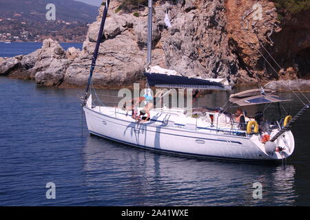 Trois garçons sous-off un bateau à voile sur une île grecque et ancrée dans une baie. Banque D'Images