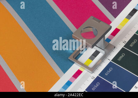 Loupe d'argent sur l'impression test permanent, l'arrière-plan de couleur. Loupe d'impression offset sur feuille imprimée avec des couleurs de base des barres de commandes. Banque D'Images