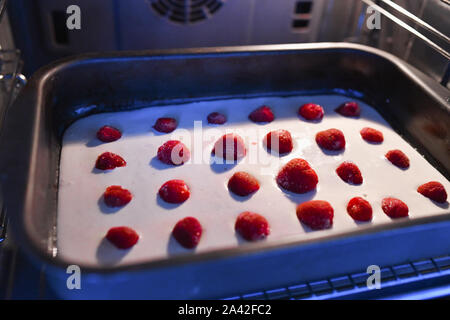 Base pour tarte aux fraises dans le four. Fraise et banane frais et sain ou tarte à la crème à tarte sur un fond de tarte golden fraîchement cuits servis sur une plaque à pâtisserie Banque D'Images