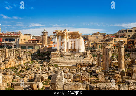 Les ruines et ne font que fragmenter de temple de Vénus à gauche avec des maisons modernes et de ciel bleu en arrière-plan, vallée de la Bekaa, Baalbeck, au Liban Banque D'Images