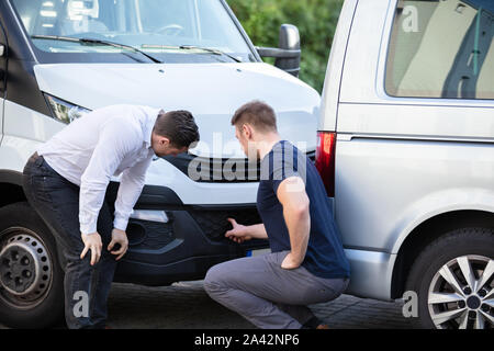 Close-up de deux hommes l'inspection de la voiture après l'accident pour les dommages Réclamation d'assurance Banque D'Images