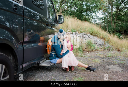 Mother and Daughter hugging en dehors d'un camper van tout en camping Banque D'Images