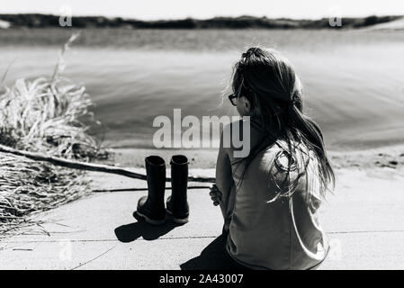 Petite fille se trouve à côté du lac avec des bottes supprimé Banque D'Images