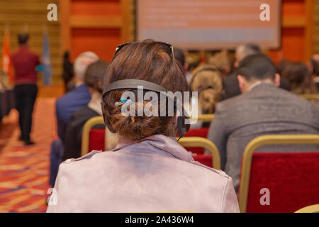 Homme avec casque à la conférence . L'auditoire wearing head phone pour traduction en ligne . À l'aide de personnes méconnaissables dans l'oreille d'écouteurs pour transl Banque D'Images
