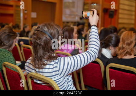 Homme avec casque à la conférence . L'auditoire wearing head phone pour traduction en ligne . À l'aide de personnes méconnaissables dans l'oreille d'écouteurs pour transl Banque D'Images