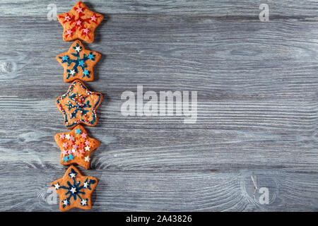 L'étoile de Noël traditionnels cookies sur table en bois gris. Une rangée de témoins sur la gauche, l'espace libre sur la droite. Contexte dans un style rustique. Banque D'Images