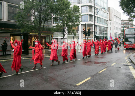 Londres, Royaume-Uni - 11 octobre 2019. La Brigade rebelle rouge de l'Extinction, rébellion, vêtu de rouge pour représenter le sang de 1000 morts ou mourants ou plus d'espèces animales et végétales à pied dans une ligne sur Oxford Street sur la cinquième journée de manifestations climatiques dans le cadre d'une campagne pour forcer le gouvernement à déclarer une urgence climatique et un engagement à mettre un terme à la perte de la biodiversité et les émissions de carbone zéro net en 2025 et pour la création d'une assemblée de citoyens sur le climat et la justice écologique. Credit : amer ghazzal/Alamy Live News Banque D'Images