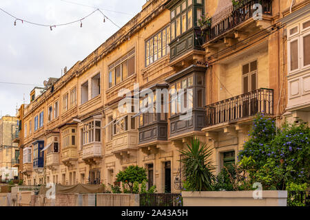 Façade de maison résidentielle avec balcons en bois traditionnelle maltaise à Sliema, Malte, colorée en orange avec la lumière du soleil du soir. Banque D'Images