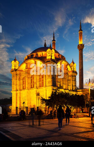 Mosquée Ortakôy à Istanbul illuminée par les lumières au coucher du soleil. Les visages des gens ne sont pas reconnaissables. La Turquie Banque D'Images