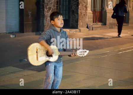 Garçon jouant de la guitare sur la rue pour l'argent avec les piétons derrière lui sur l'avenue 5 de Mayo, Centro Historico, Mexico, Mexique Banque D'Images