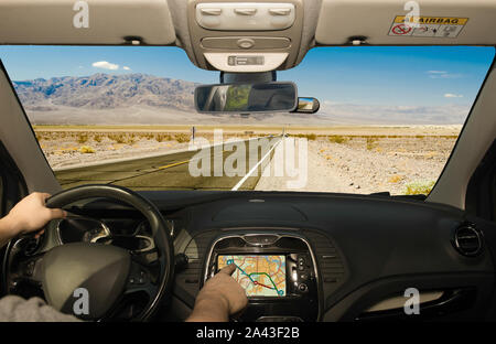 La conduite d'une voiture tout en utilisant l'écran tactile d'un système de navigation GPS sur une route du désert dans la région de Death Valley National Park, California, USA Banque D'Images