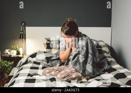 Femme malade avec le nez, assis au lit. femme malaise et éternuez chambre à coucher. Femme tenant ,tissus les symptômes de la grippe. Concept médical Santé Banque D'Images