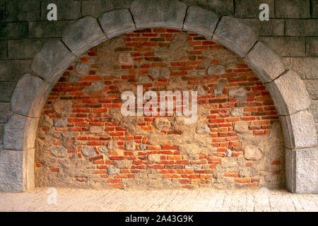 Mur de briques colorées mélangées à la lumière des pierres naturelles. Arrière-plan de béton et briques mixte. Arch a fait de blocs de béton et briques orange. Banque D'Images