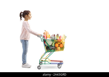 Profil de pleine longueur tourné d'une petite fille l'achat de fruits et légumes dans un mini panier isolé sur fond blanc Banque D'Images