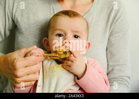 Bébé âgé de 5 mois de manger une cuisse de poulet à l'aide de l'enfant conduit le sevrage BLW méthode. Banque D'Images