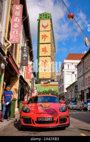 Une Porsche rouge est garée dans le pittoresque Temple Street, Chinatown, Singapour, l'ajout d'un premier plan de couleur jaune à la People's Park Complex derrière Banque D'Images