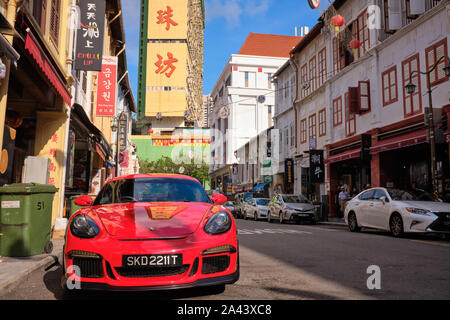 Une Porsche rouge est garée dans le pittoresque Temple Street, Chinatown, Singapour, l'ajout d'un premier plan de couleur jaune à la People's Park Complex derrière Banque D'Images