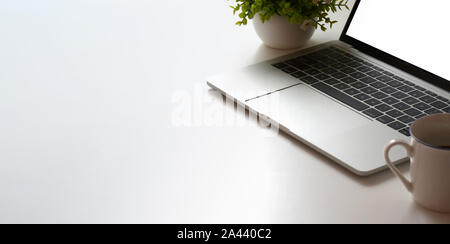 Cropped shot d'un volume minimal d'espace de travail avec ordinateur portable et pot de l'arbre blanc sur la table tableau et Coffee cup Banque D'Images