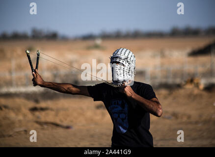 Un manifestant palestinien utilise une fronde pour lancer des pierres au cours d'une manifestation anti-Israël, appelant à mettre fin à des années de siège sur la frontière Israel-Gaza au sud de Gaza. Banque D'Images