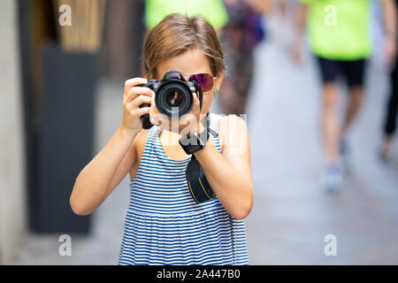 Petite fille en photo avec votre appareil photo reflex numérique on city street Banque D'Images