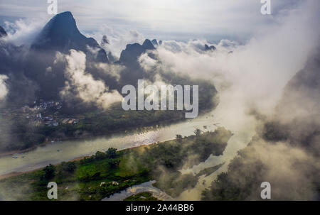Les montagnes et les collines sont entourés de brume et de nuages le long de la rivière Li au lever du soleil dans le comté de Yangshuo, Guilin, Chine du sud est une région autonome Zhuang du Guangxi Banque D'Images