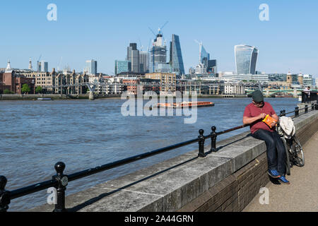 Londres, Angleterre - 15 mai 2018 : un homme prend une pause sur le bord de la rivière Thames, sur une journée ensoleillée Banque D'Images
