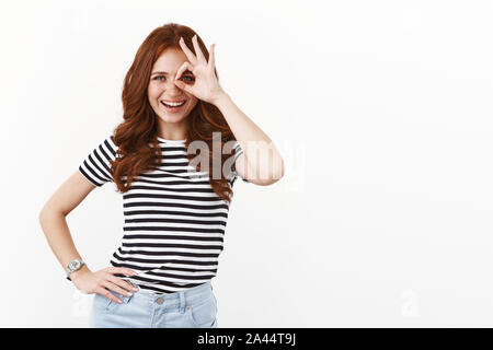 Bien ambitieux redhead flirty femme T-shirt à rayures en long, bouclés gingembre coiffure, regardant à travers les doigts, visent la réussite, sta Banque D'Images