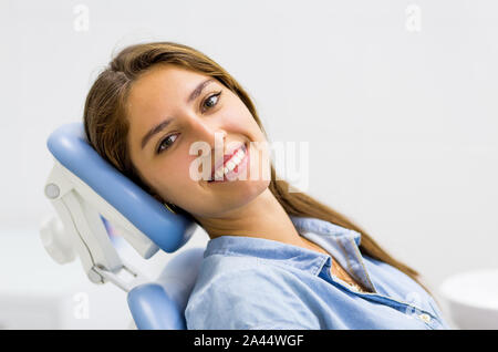 Jeune femme visite chez le dentiste et souriant assis dans fauteuil dentaire. Banque D'Images