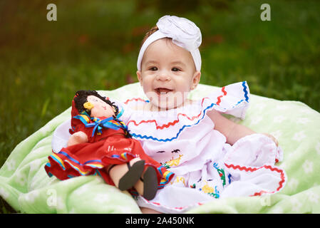 Smiling baby en robe sur fond d'herbe verte brouillée Banque D'Images