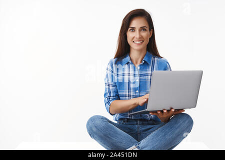 Bureau, freelance, Nomad Digital concept. Ambitieux joyeux femme d'âge moyen à distance de travail, s'asseoir jambes croisées près de l'ordinateur portable, smartphone, maintenir, de travail Banque D'Images