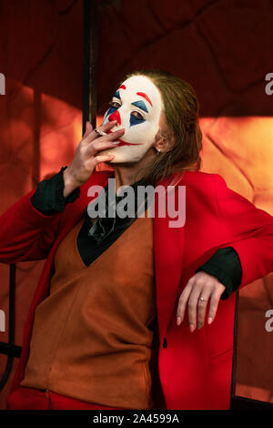 Jeune femme avec Joker costume maquillage et fumeurs Banque D'Images