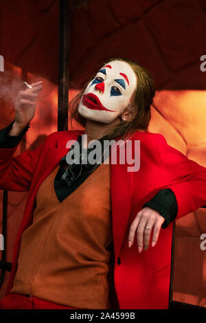 Jeune femme avec Joker costume maquillage et fumeurs Banque D'Images
